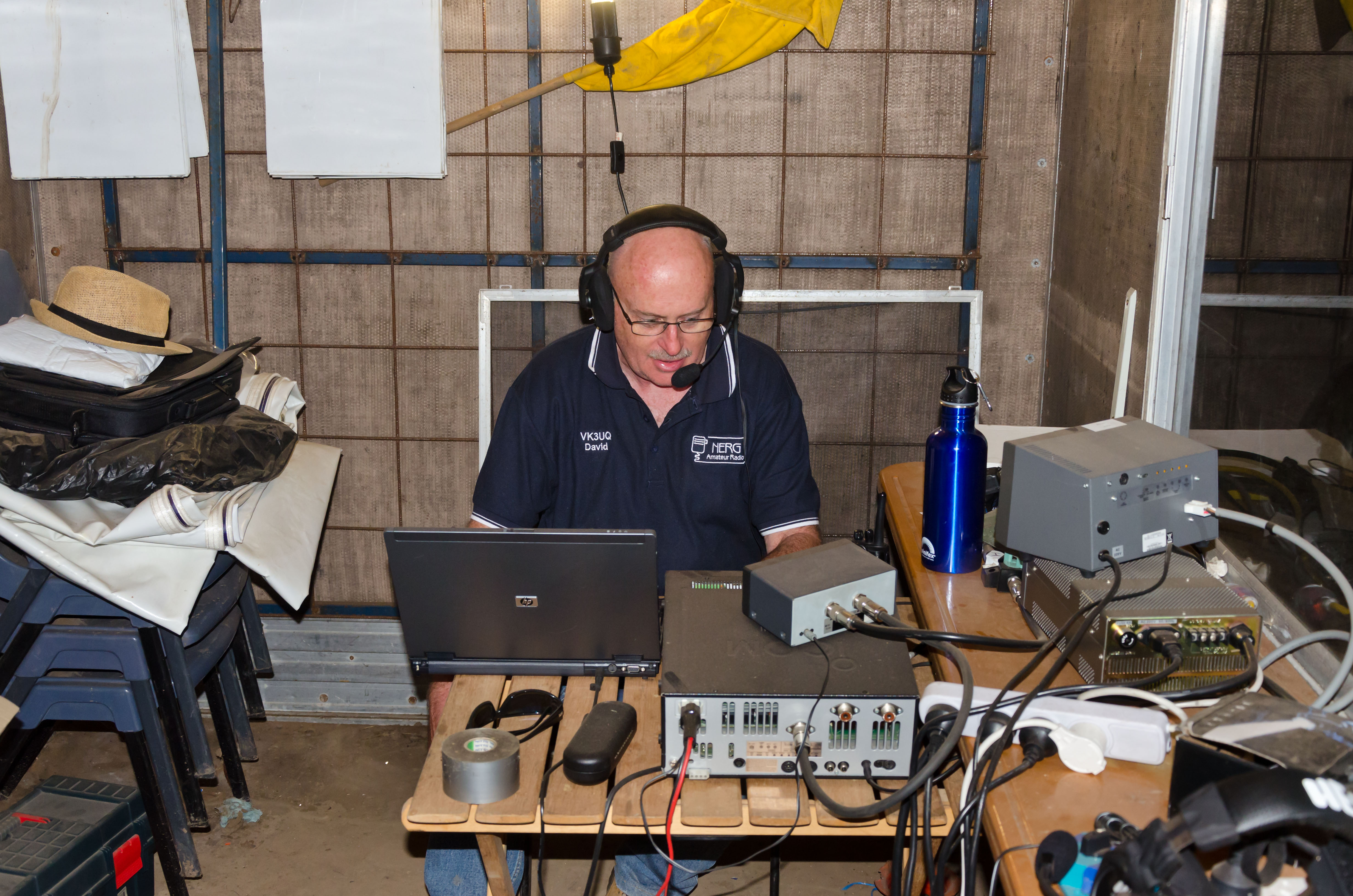 A man wearing a headset operating a radio and computer.